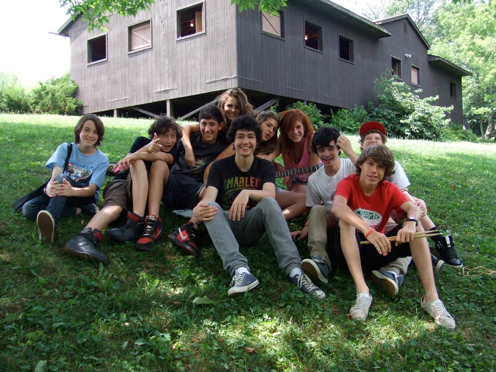 Group of Camp Ballibay campers sitting together on a green lawn at summer camp.