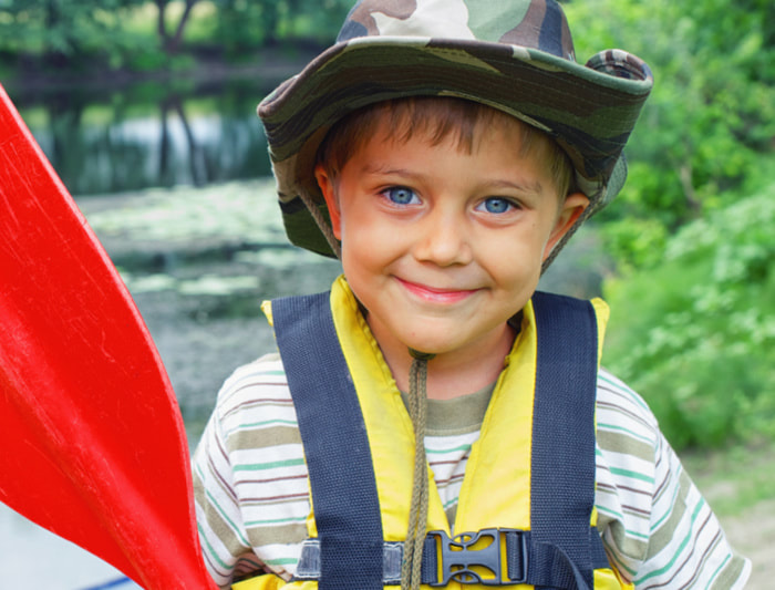 Boy holding a canoe paddle at the lake at summer camp