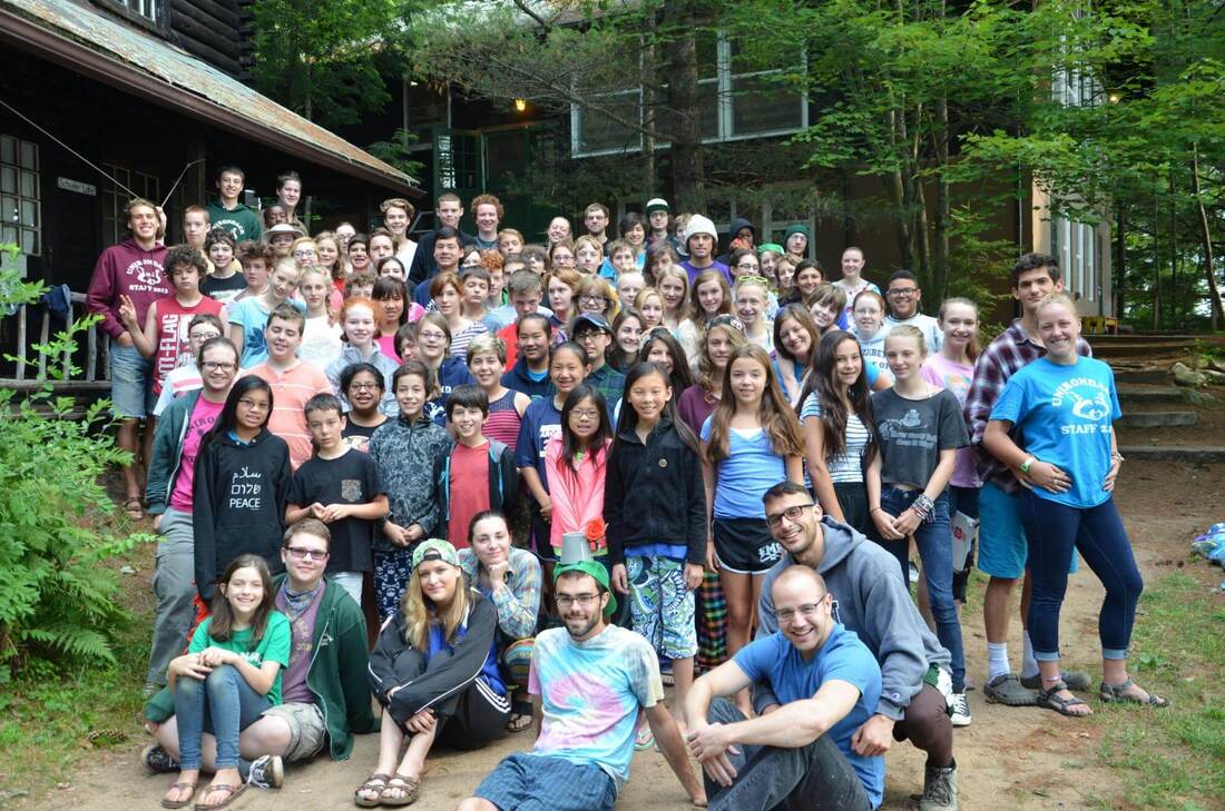 Group of campers and counselors in front of their cabins at Camp Unirondack Summer Camp