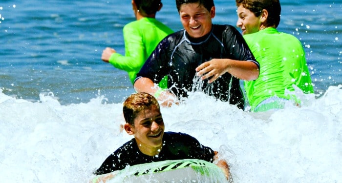 Boys enjoying the sport of boogie boarding at summer camp.