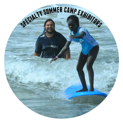 Girl learning to surf with her surf camp summer camp instructor smiling in the background at summer camp.